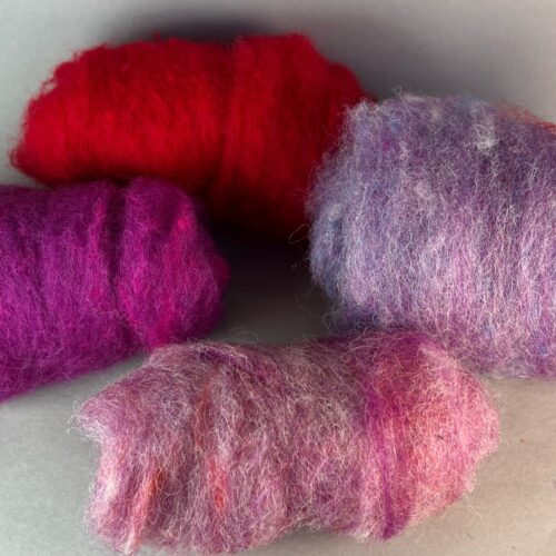 Needle Felted Heart Kit. Four rolls of dyed fleece, red, purple, lavender, and pink.