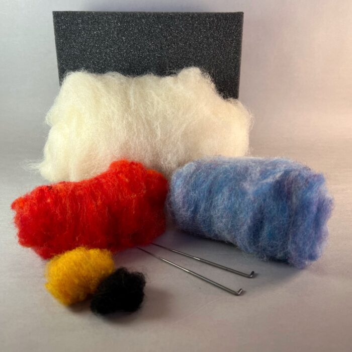 Needle Felted Owl Kit. Five different colors of wool are arranged in front of a grey foam mat. Two felting needles are beside the wool.