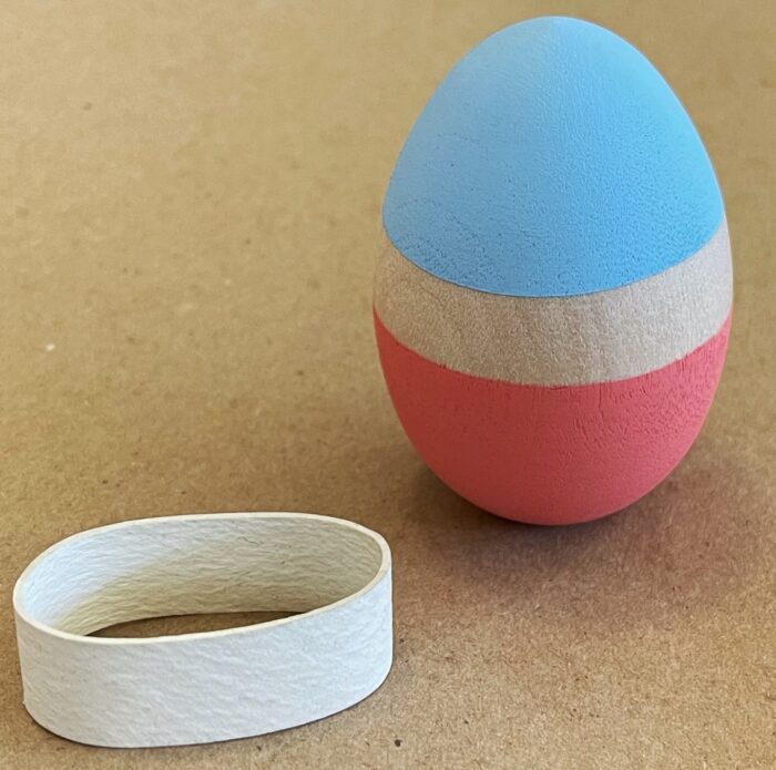 Egg Decorating Kit. One wooden egg, painted light blue on the top and coral on the bottom, with an unpainted stripe between the two colors.